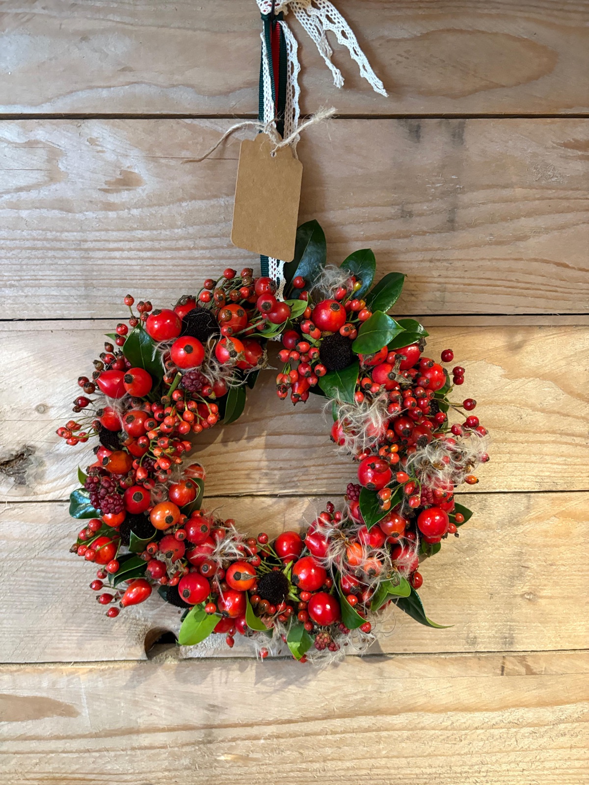 Herbstlicher Kranz aus Hagebutten und Beeren an der Holzwand